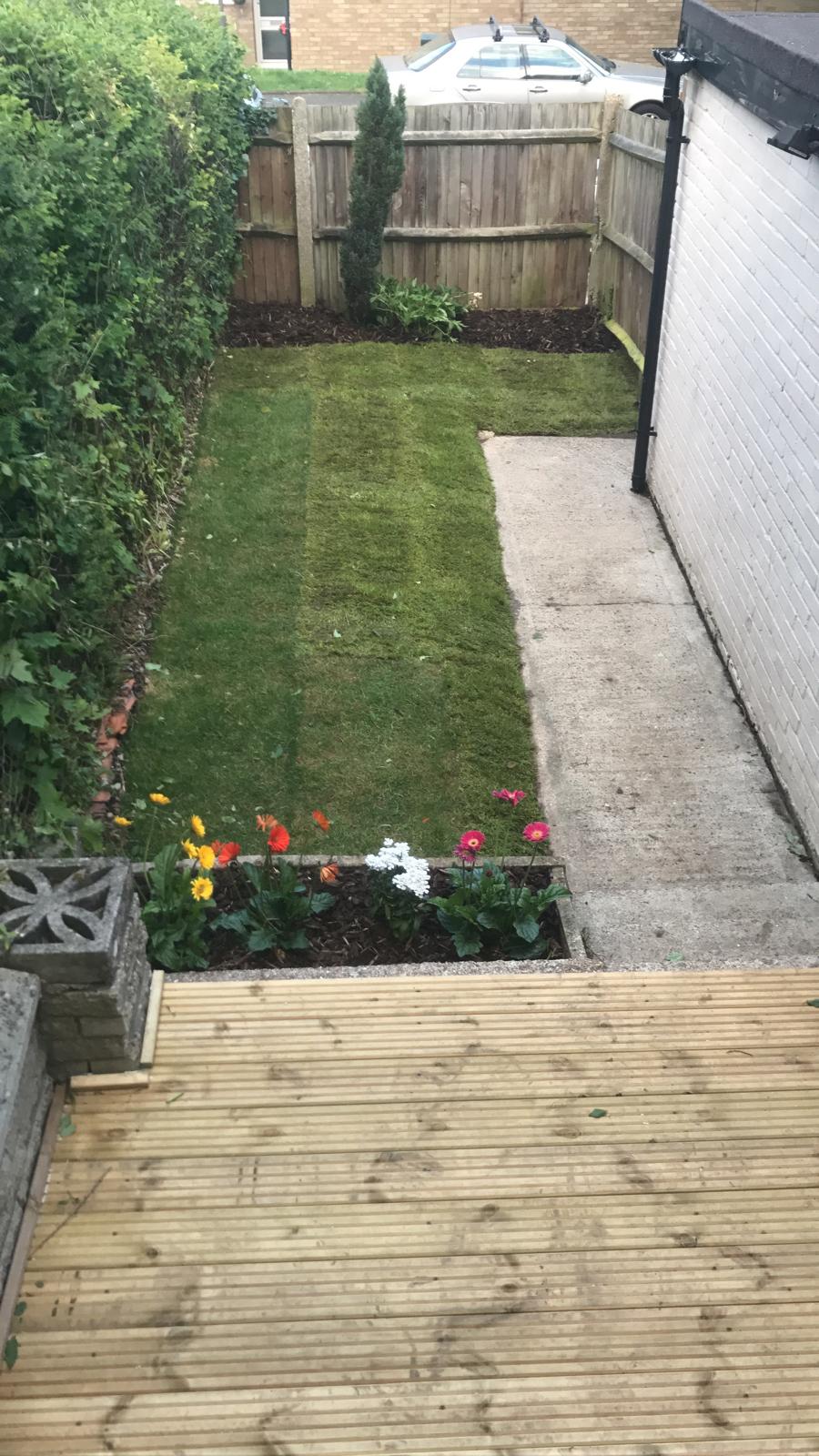 Rear garden with newly laid lawn, planting bed and timber decking