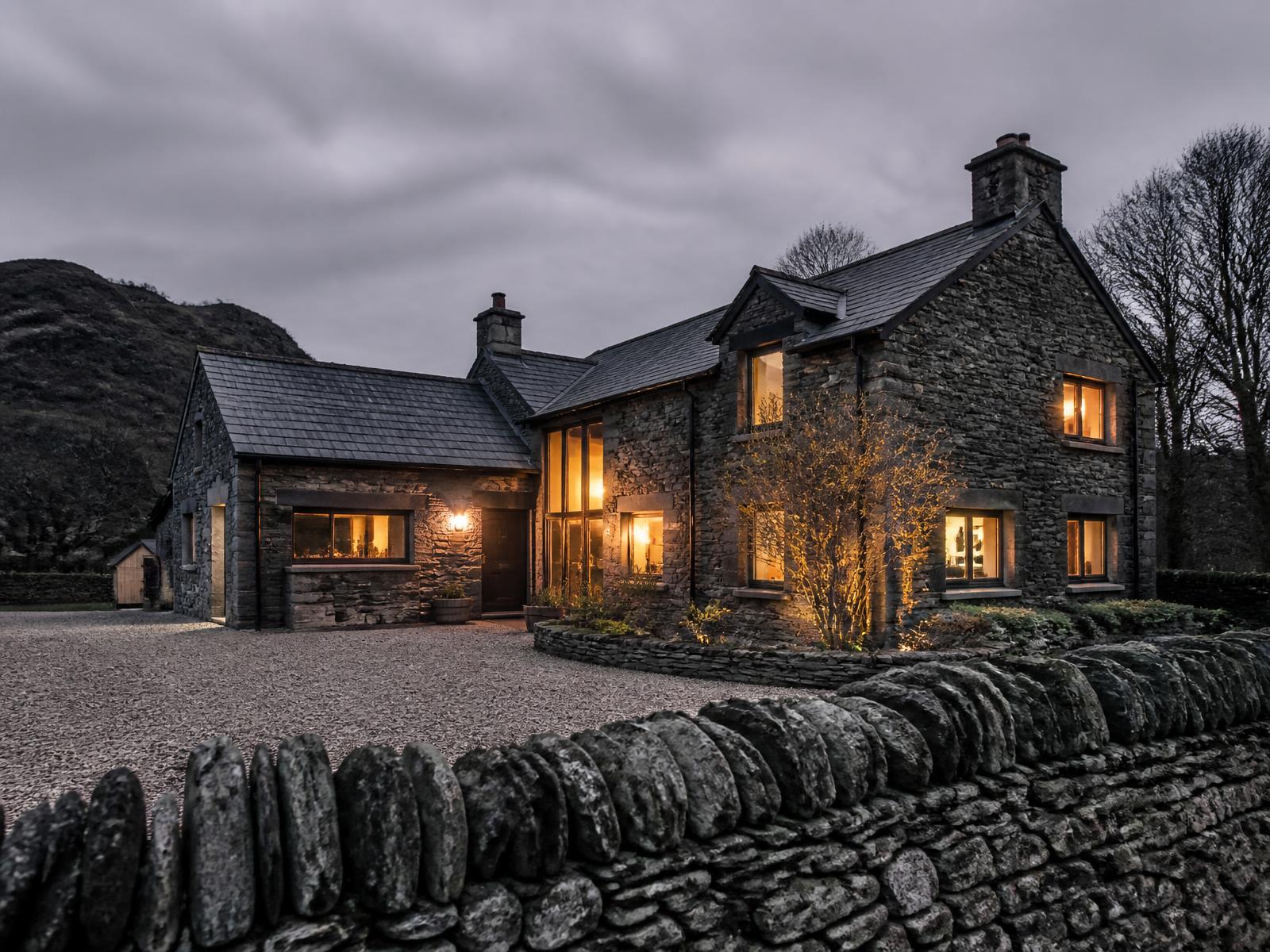 Renovated stone cottage at dusk with lit windows